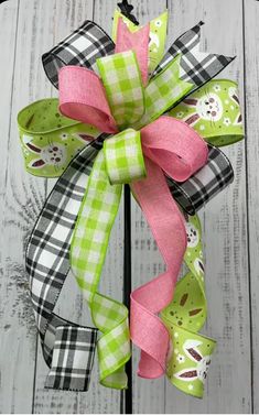 a green and pink bow on top of a metal pole with white wood boards in the background