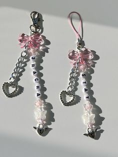 two pairs of pink and white earrings with hearts on them, hanging from silver chains