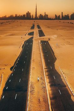 an aerial view of a highway in the middle of desert with skyscrapers in the background