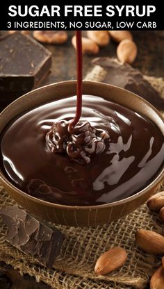 chocolate ganache sauce being poured into a bowl with nuts on the side and then drizzled over it