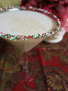 a close up of a martini in a glass on a table with red, white and green decorations