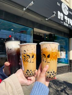 two people holding up drinks in front of a building with the words bbt taco written on it