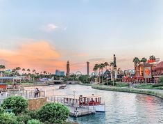 a river that has boats on it and some buildings in the background with palm trees