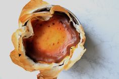 a baked pastry in a metal bowl on a white table top, with the crust removed from it