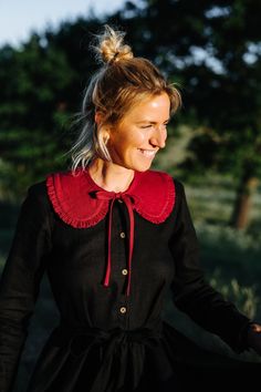 a woman wearing a black dress with red collar