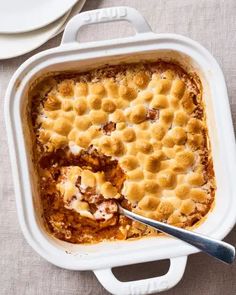 a casserole dish with meat and cheese in it on a table next to plates