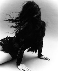 black and white photograph of a woman laying on the ground with her hair blowing in the wind