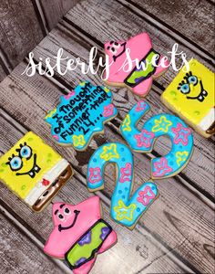 some decorated cookies are sitting on a wooden table with the words, sisterly sweets