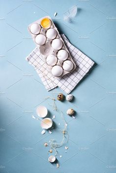 an overhead view of eggs and flowers on a blue background