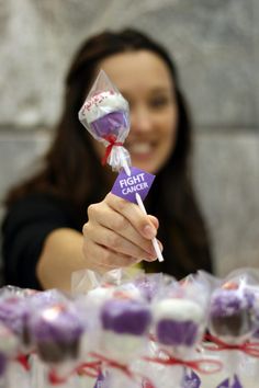 a woman holding up a lollipop in front of many other candies on display