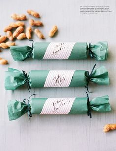 three rolls wrapped in green paper and tied with twine, sitting next to peanuts