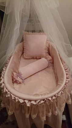 a baby bassinet with a pink blanket and pillow on it's side