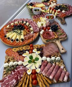 an assortment of meats and cheeses on platters for a buffet or party