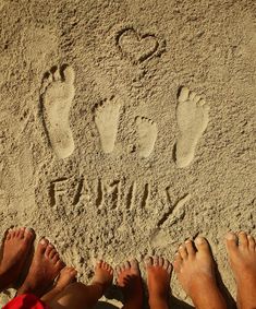 three people are standing in the sand with their feet up and one person is writing on it