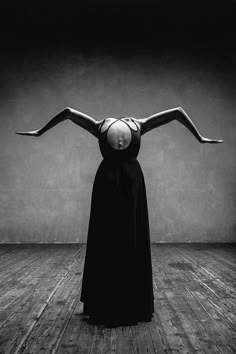 a woman in a black dress is balancing her arms over her head with both hands