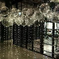 some shiny balls hanging from the ceiling in front of a mirror with lights on it