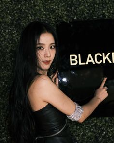 a woman in black dress posing for the camera with her arm around a sign that says blackberry