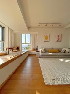 an empty living room with wood floors and white walls, along with large windows overlooking the ocean