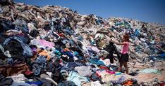 a woman standing in front of a pile of clothes on top of a dirt hill