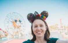 a woman with mouse ears standing in front of a ferris wheel