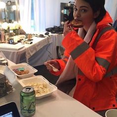 a woman in an orange jacket eating food