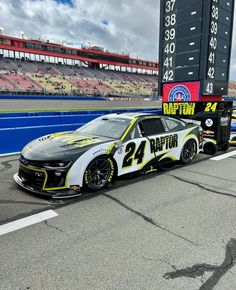 a race car driving down the track in front of a scoreboard