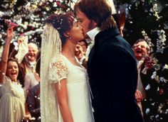 a man and woman kissing in front of a crowd of people at a wedding ceremony