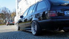 a black car parked in front of a white building on a cobblestone street