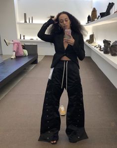 a woman is taking a selfie with her cell phone in a shoe store while wearing black pants and heels