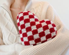 a woman holding a crocheted heart in her arms