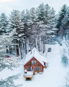 an aerial view of a cabin in the woods with snow on the ground and trees