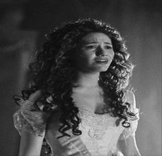 a woman with long curly hair wearing a white dress