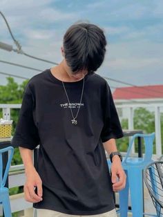 a young man standing on top of a wooden deck wearing a black shirt and khaki pants