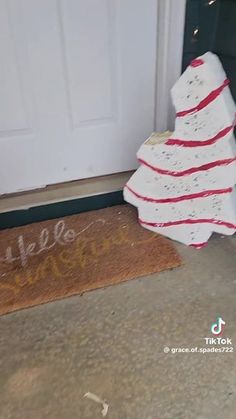 a white christmas tree sitting in front of a door with the word welcome written on it