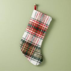 a plaid christmas stocking hanging on a green wall