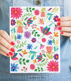 a woman holding up a card with colorful flowers on it