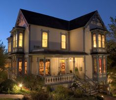 a large white house at night with lights on the front porch and stairs leading up to it