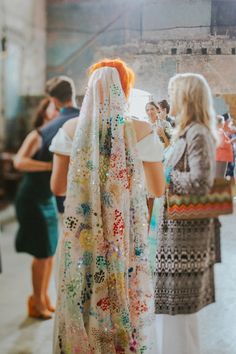 a group of women standing next to each other in front of a window covered in sequins