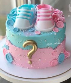 there is a cake decorated with baby shoes and buttons on top of the cake, as well as a question mark