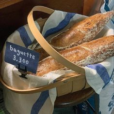 two loaves of bread in a basket with a price tag on it and another baguette sign