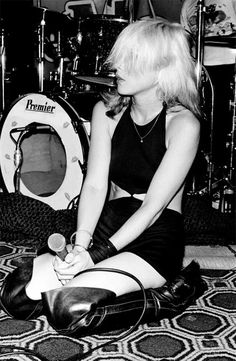 a woman sitting on the floor next to a drum set