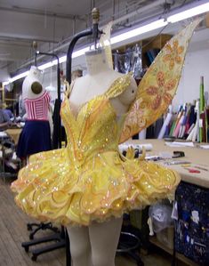 a mannequin wearing a yellow dress in an art shop with other items on the table