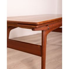 a close up of a wooden table on a hard wood flooring area with white walls in the background