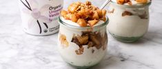 two jars filled with food sitting on top of a marble counter next to an ice cream container