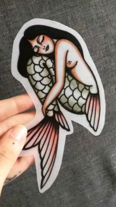 a person holding up a sticker with an image of a mermaid on it's back