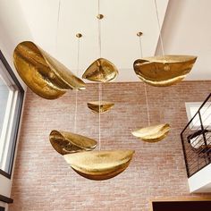 a room filled with lots of gold colored objects hanging from the ceiling next to a brick wall