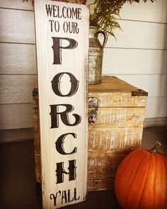 a wooden sign that says porch y'all next to a box with a pumpkin