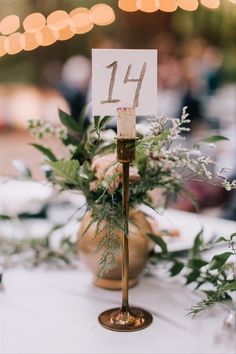 the table numbers are displayed on small candlesticks with greenery and white flowers