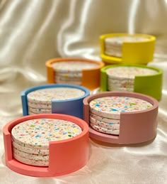 four colorful coasters with sprinkles on them sitting on a white cloth