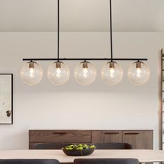 a dining room table with four lights hanging over it